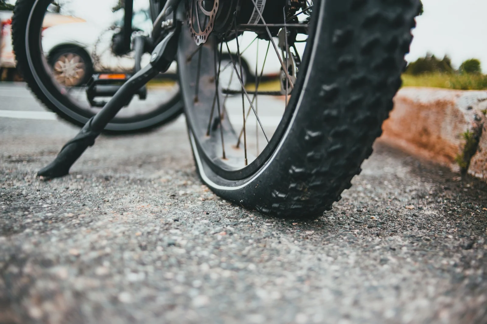 Detailed image of a flat bicycle tire on asphalt, illustrating outdoor roadside repair needs.