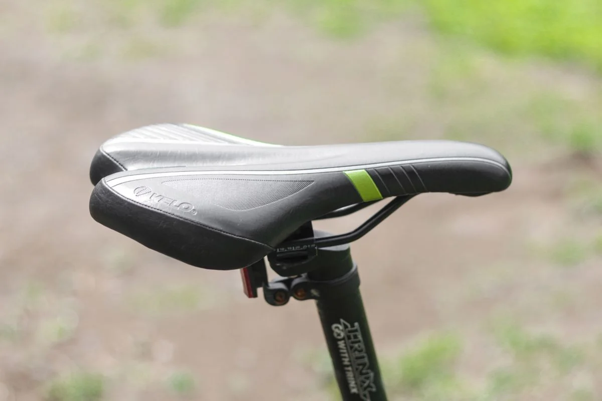 Close-up view of a black bicycle saddle in an outdoor setting, capturing details.