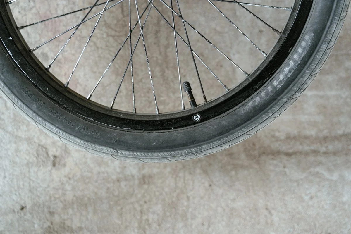 Detailed close-up of a bicycle wheel showing the spokes and valve on a concrete surface.