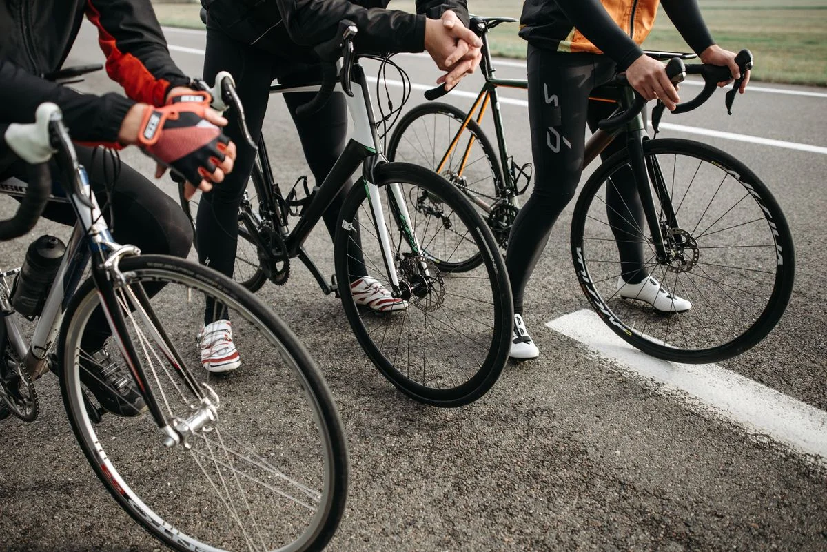 Group of cyclists with modern road bikes getting ready for a competitive ride on asphalt road.